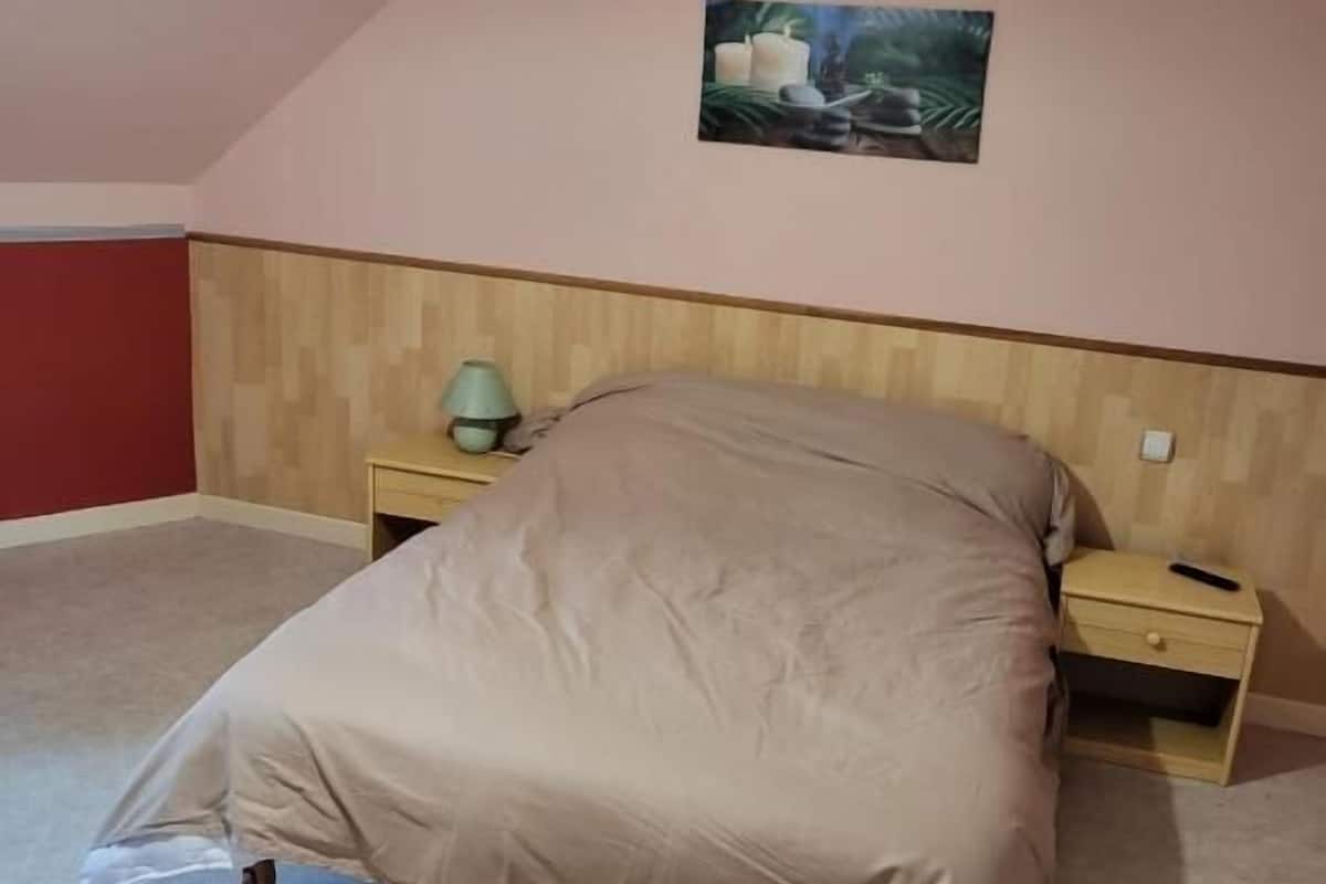 A bedroom with a bed, nightstands, a lamp, and a painting on the wall.