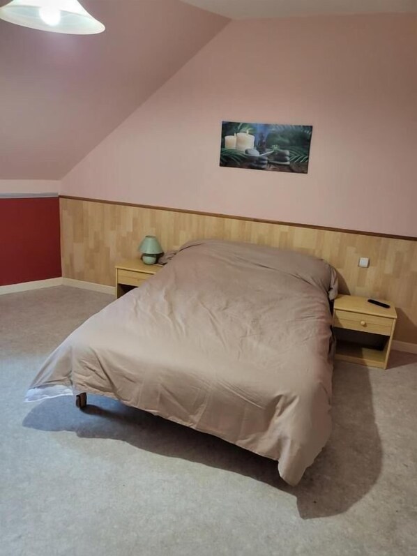 Une chambre à coucher avec un lit, des tables de chevet, une lampe et un tableau au mur.