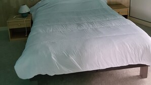 Ein Schlafzimmer mit einem Bett, einem Nachttisch, einer Lampe, einem Bild an der Wand und einem Kleiderschrank.