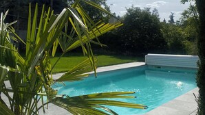 Una piscina rodeada por un jardín con palmeras y césped.