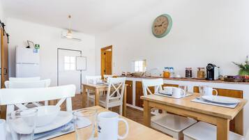 Cozinha moderna com eletrodomésticos brancos, mobiliário de madeira e um relógio na parede.