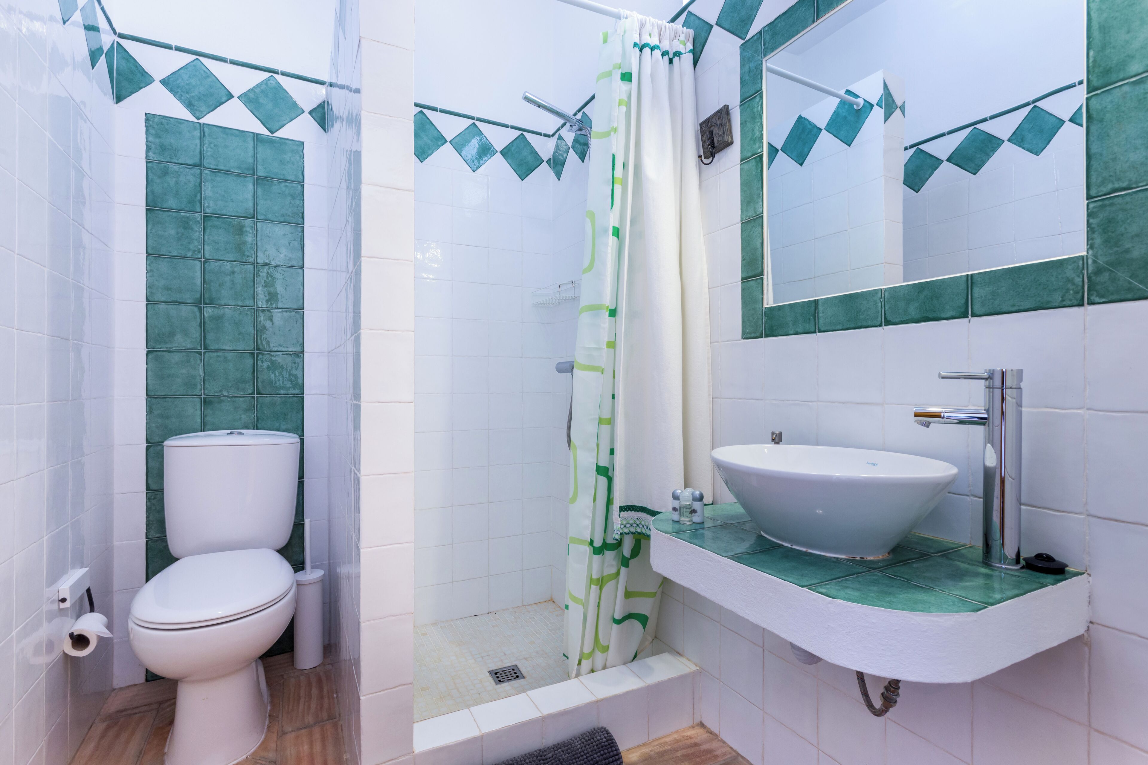 Une salle de bain équipée de toilettes, d’une douche, d’un lavabo et d’un miroir.