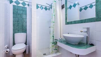 Un baño con inodoro, ducha, lavamanos y espejo.