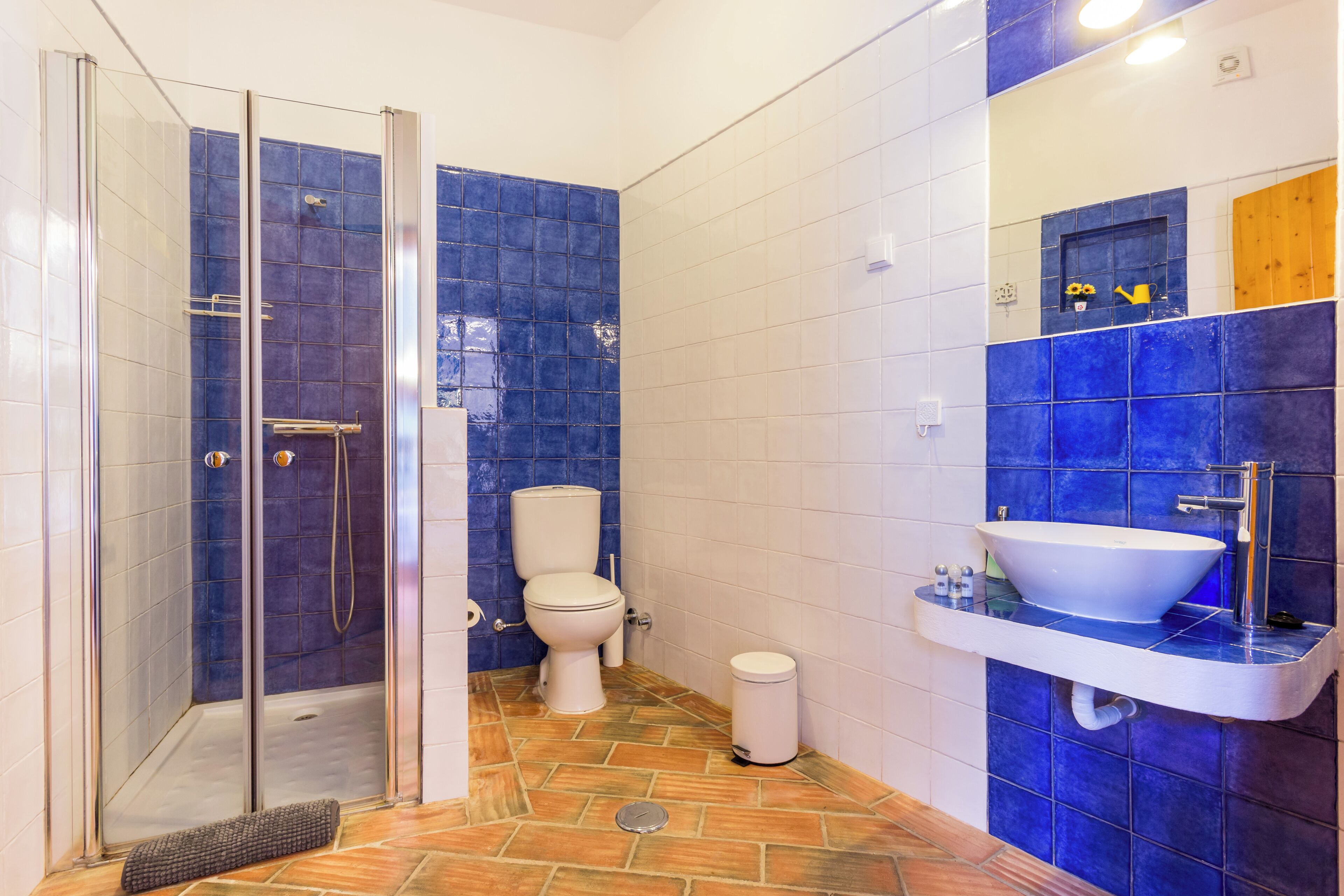 A bathroom with a glass shower enclosure, a toilet, and a sink with a mirror above it.