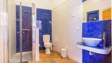 A bathroom with a glass shower enclosure, a toilet, and a sink with a mirror above it.