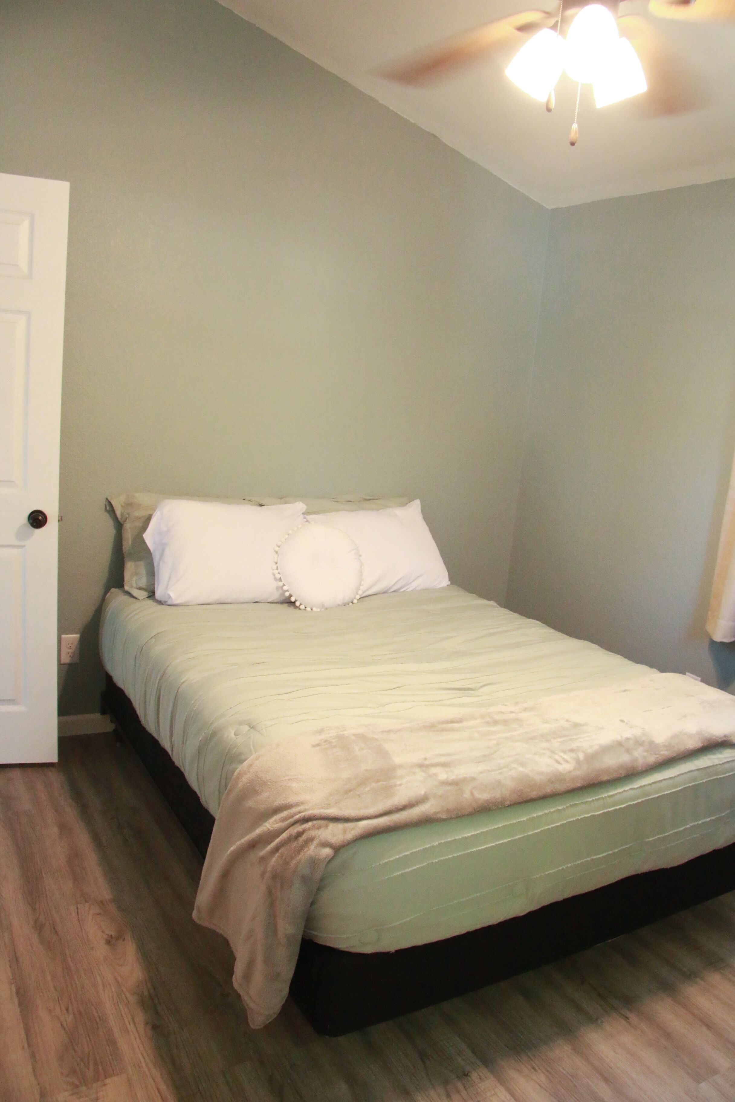 Une chambre à coucher avec un lit, un ventilateur de plafond et une porte.