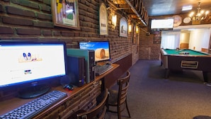 A room with brick walls, a pool table, and multiple computer stations with monitors and keyboards. - Travel (Amsterdam)