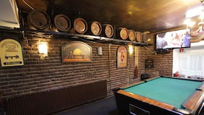 A billiards room with a pool table, brick walls, and a television mounted above it. - Travel (Amsterdam)