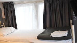A single bed with white bedding, a black blanket, and a folded white towel. - Travel (Amsterdam)