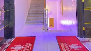 Eine Hotelhalle mit Treppe, roten Willkommensmatten und einer Rezeption.