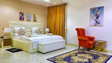 Un dormitorio moderno con una cama grande, un sillón rojo y una alfombra azul estampada.