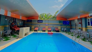 Ein Schwimmbecken mit freiem Blick zum Himmel, umgeben von Liegestühlen und einer Bar.