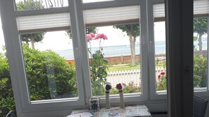 Una habitación con vista al mar, una mesa con un florero y una silla.