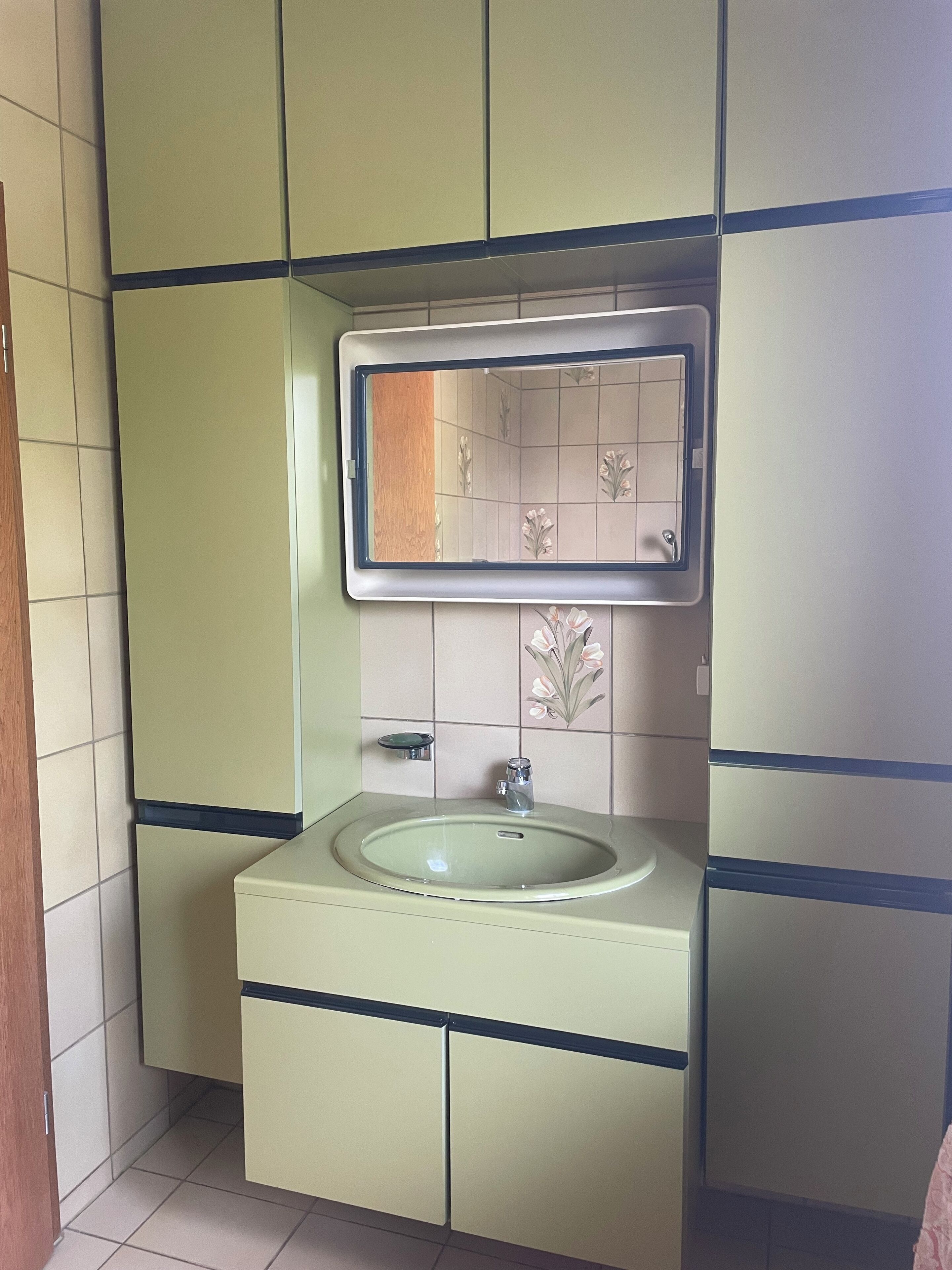 A bathroom with a sink, mirror, and tiled walls.