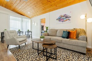 Un salon comprenant un canapé, des fauteuils, une table basse et un tapis à motifs léopard.