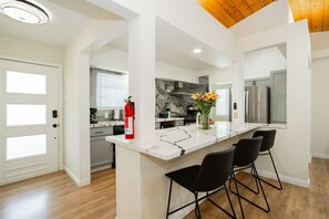A modern kitchen with a marble countertop, black chairs, and a fire extinguisher.