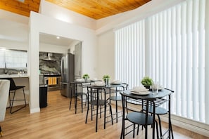 A modern kitchen with a marble backsplash, stainless steel appliances, and a dining area with black chairs and a table set for four.