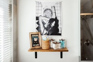 Une étagère murale avec un tableau encadré, un panier et deux bocaux en verre.