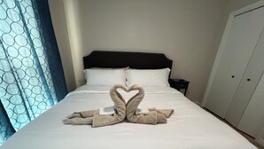 Una habitación de hotel con una cama, una mesita de noche y un armario.