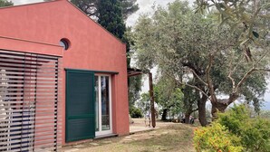Un edificio moderno con facciata rossa, porta verde e recinzione in legno.