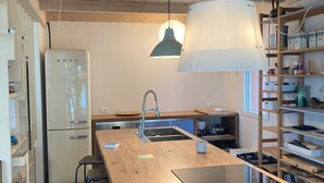 Una cucina moderna con mobili in legno, un'isola centrale con lavello e illuminazione a sospensione.