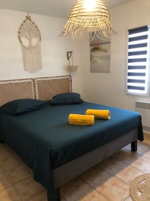 Relax in this serene bedroom with a large bed, woven ceiling light, and a unique wall decoration.