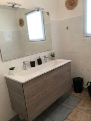 Bathroom features a large mirror above a vanity with a drawer unit and countertop.