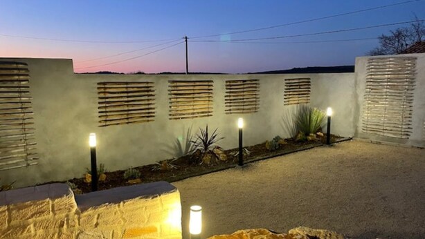 A well-lit outdoor area with a stone wall, a gravel path, and a series of lights along the wall. - Villa Mapokia 2 Climatisée Avec Piscine Chauffée Privative Proche Uzès (st marcel de careiret)