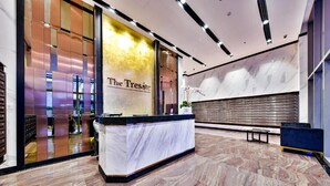 A hotel reception area with a marble reception desk, a large mirror, and a wall with a gold finish. - The Tresor Apartment Quan 4 (Ho Chi Minh City)
