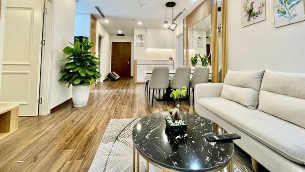 A modern living room with a sofa, a round coffee table, and a dining area with chairs. - The Tresor Apartment Quan 4 (Ho Chi Minh City)