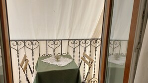 Ein Balkon mit einem Tisch für zwei Personen, einer weißen Tischdecke und einer Spitzendecke.
