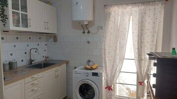Una cocina funcional con lavabo, armarios y lavadora.