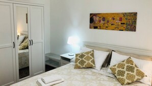 Ein Schlafzimmer mit einem Bett, einem Nachttisch, einer Lampe, einem Kleiderschrank und einem Bild an der Wand.