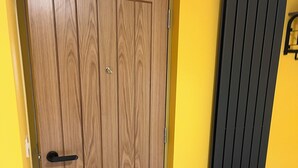 A wooden door with a handle, a radiator, and a yellow wall. - Tumbledown Hotel (Shrewsbury)