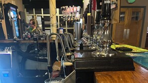 A bar area with a wooden counter, a tap, and glasses. - Tumbledown Hotel (Shrewsbury)