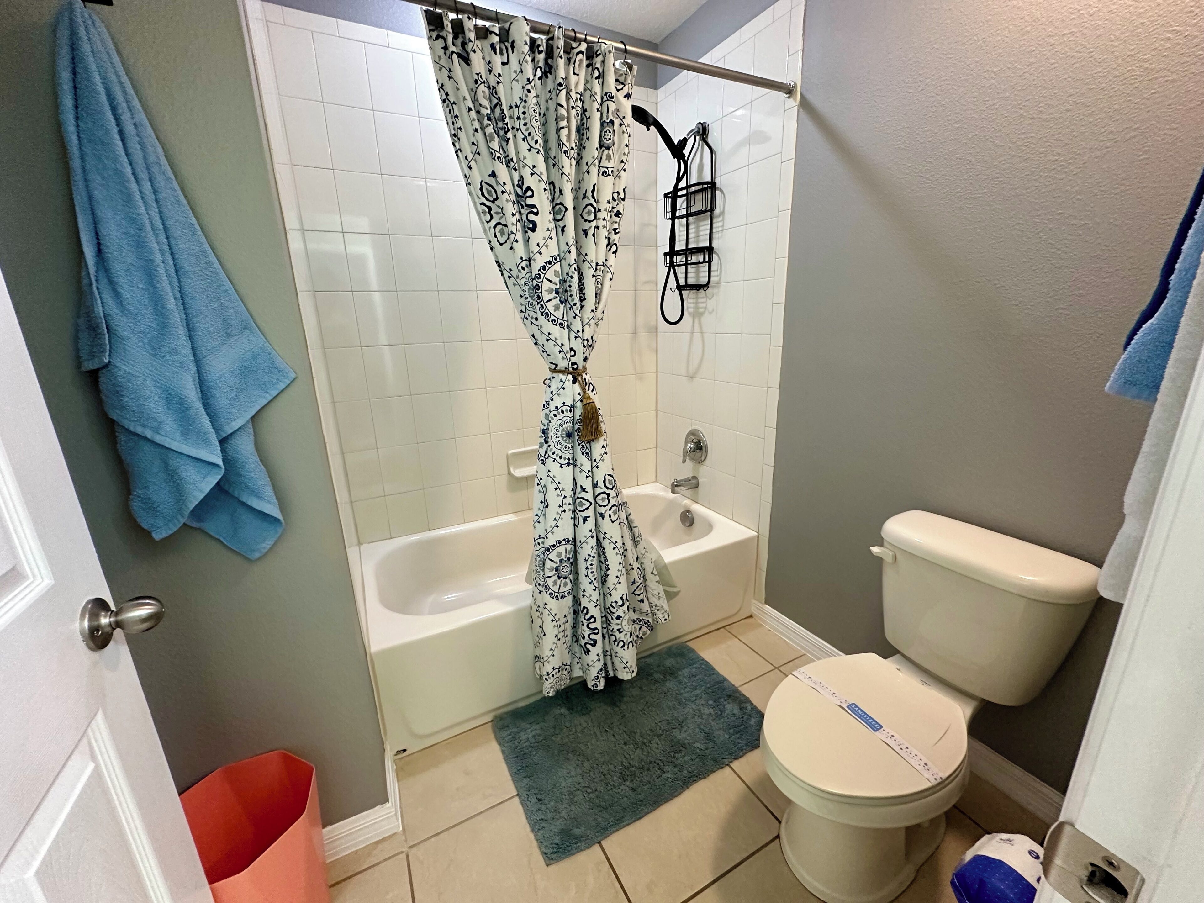 Un baño con bañera, inodoro y cortina de ducha.