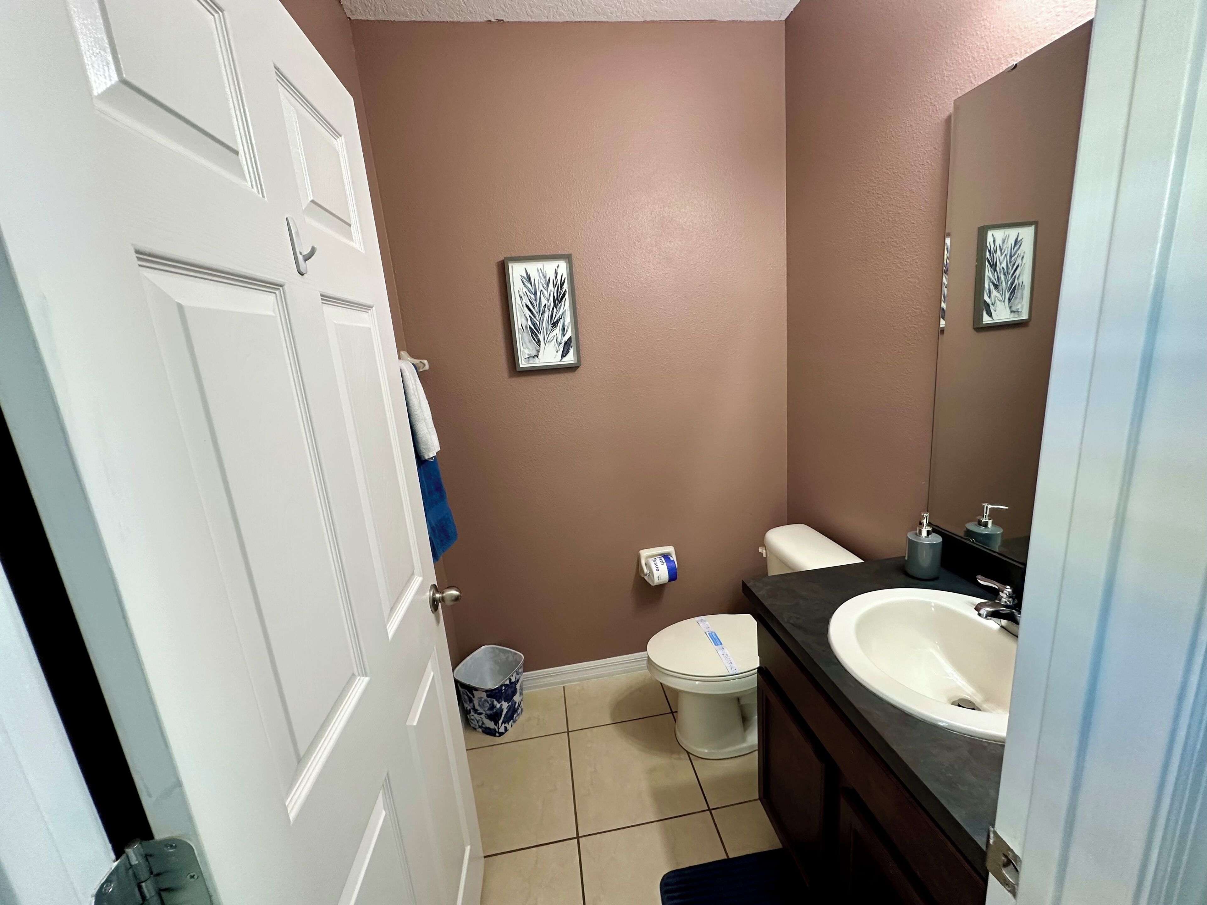 A compact bathroom with a toilet, sink, and a small trash bin.