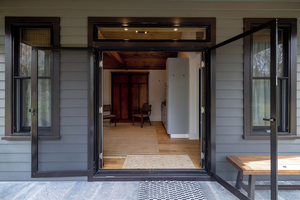 A doorway leading to a room with a wooden floor, a bench, and a patterned rug.