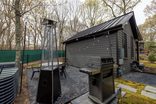 Een achtertuin met een barbecue, schoorsteen en een kleine schuur.
