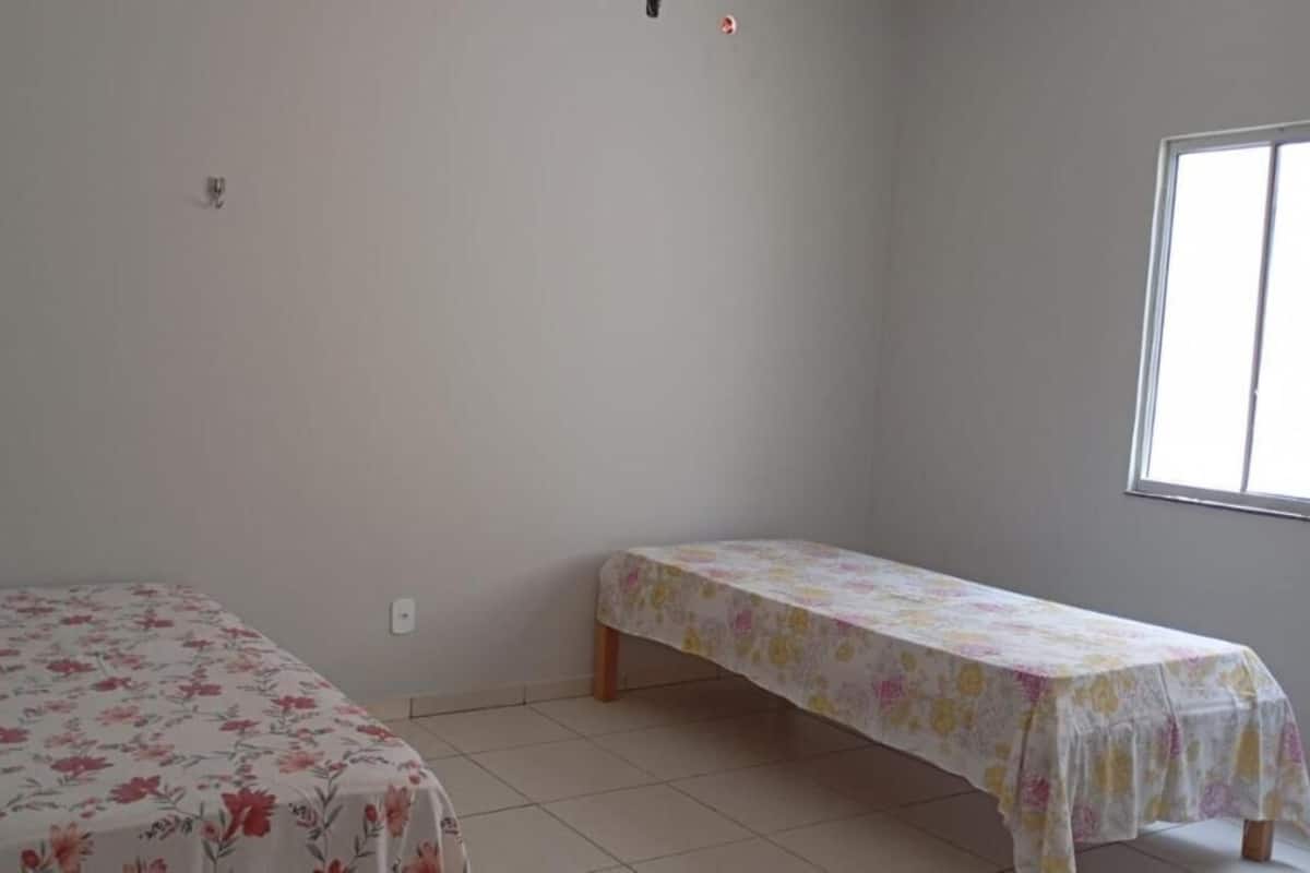 A room with two single beds, a window, and a plain wall.
