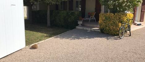 Una casa con camino de grava, un porche cubierto y una bicicleta estacionada afuera.
