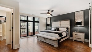 Een slaapkamer met een groot bed, een plafondventilator, een nachtkastje en uitzicht op het balkon.
