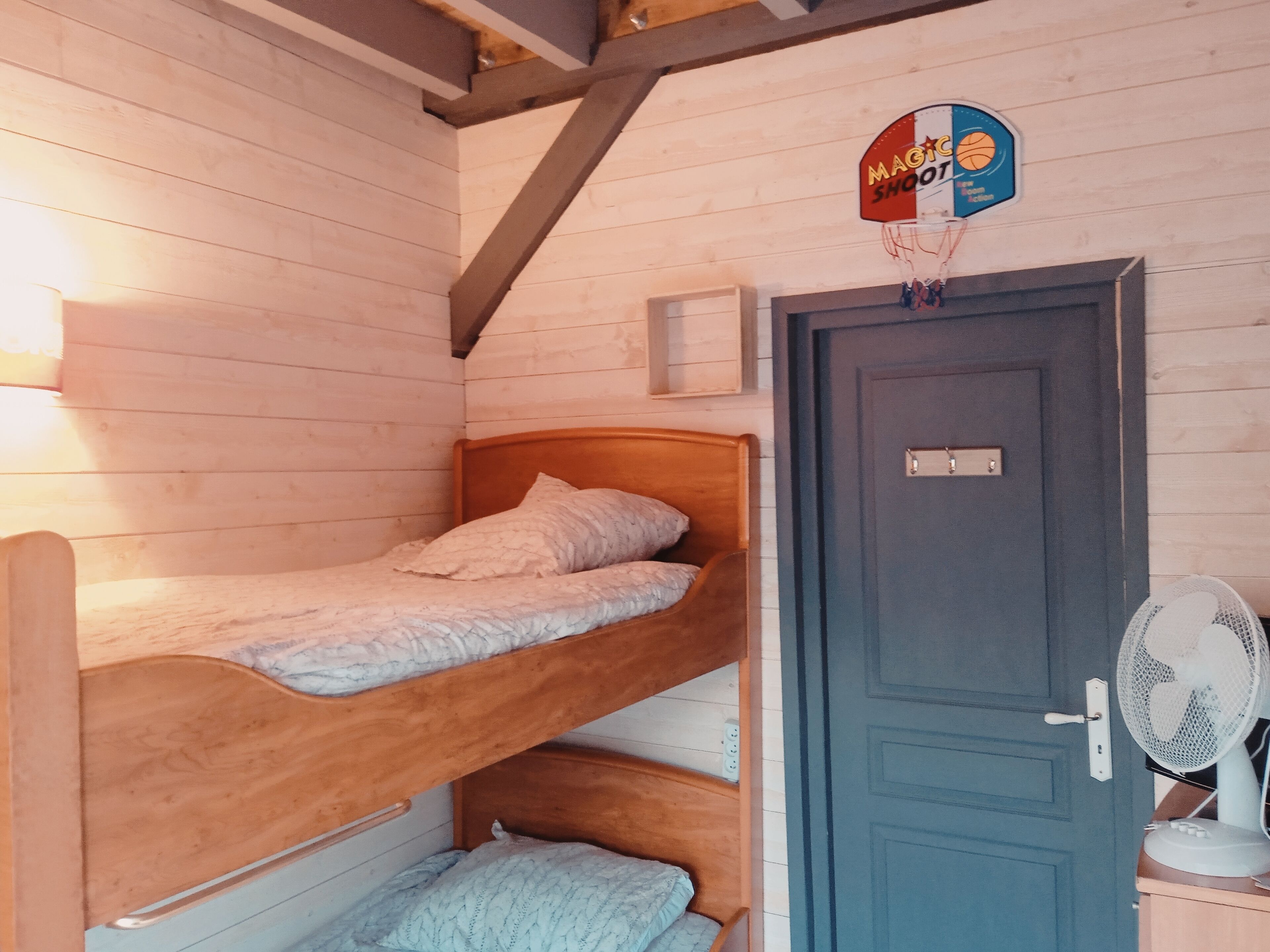 A bunk bed room with a door and a wall-mounted fan.