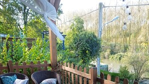 A patio with wicker furniture, a table, and a view of a lake.