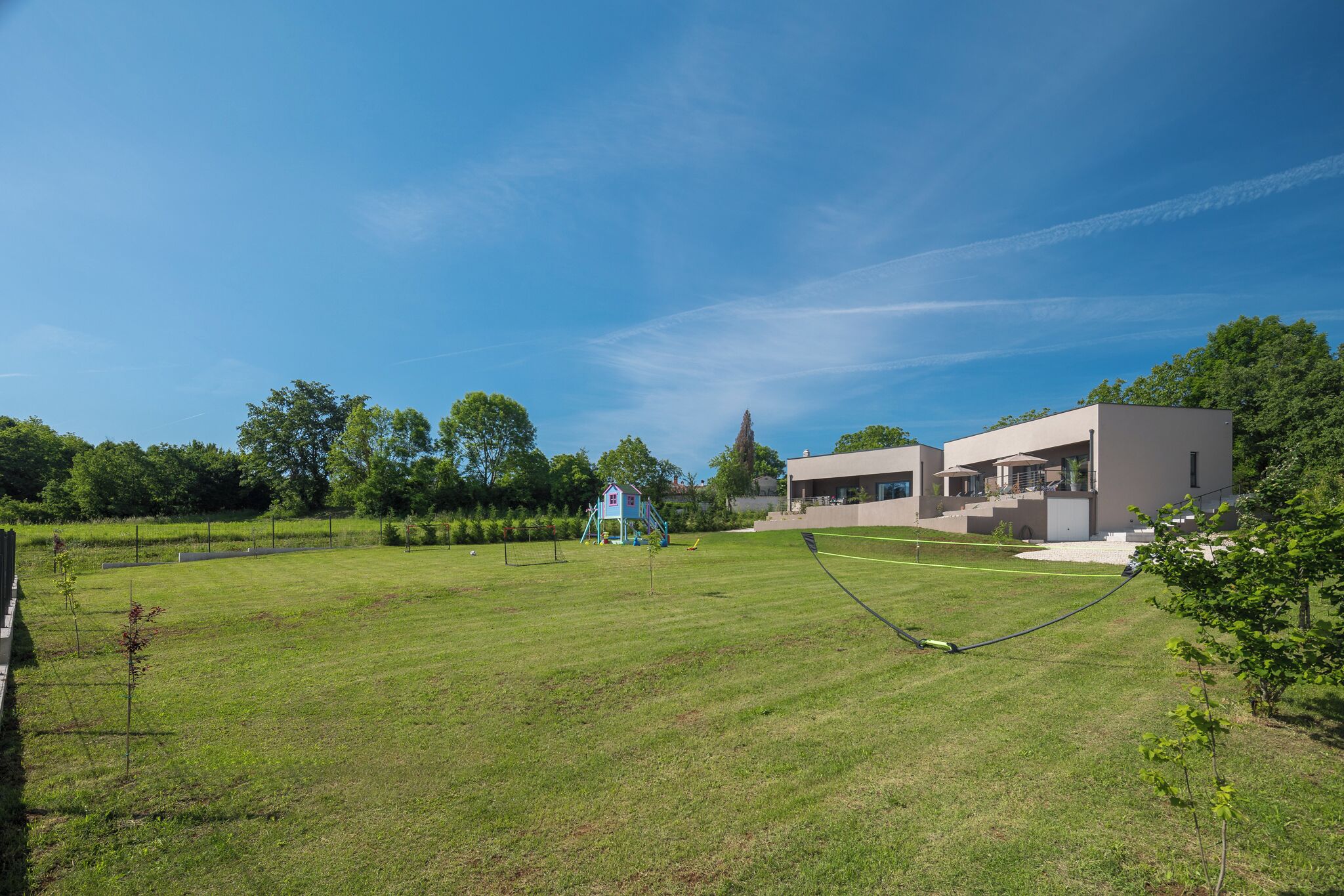 A modern building with a flat roof and large windows, surrounded by a well-maintained lawn and trees.