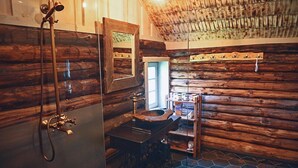 Een rustieke badkamer met houten wanden, een houten wastafel en een douche met een messing kraan.