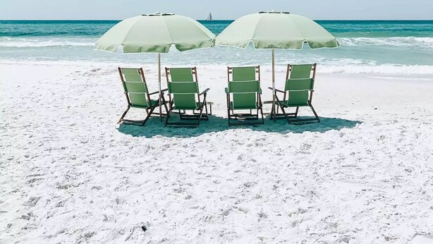 A beach with four green lounge chairs and two white umbrellas. - Brand New Luxury Beach House - Hot Tub (Galveston)