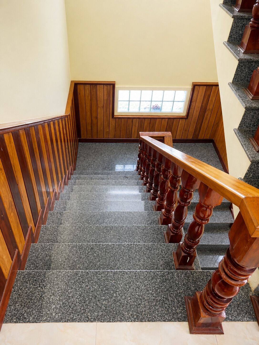 A staircase with wooden balusters and a handrail, leading to a landing with a window.