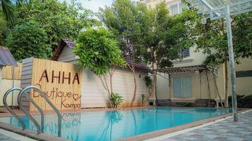 Una piscina al aire libre, sombrillas, sillones reclinables de piscina