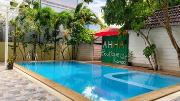 Una piscina al aire libre, sombrillas, sillones reclinables de piscina